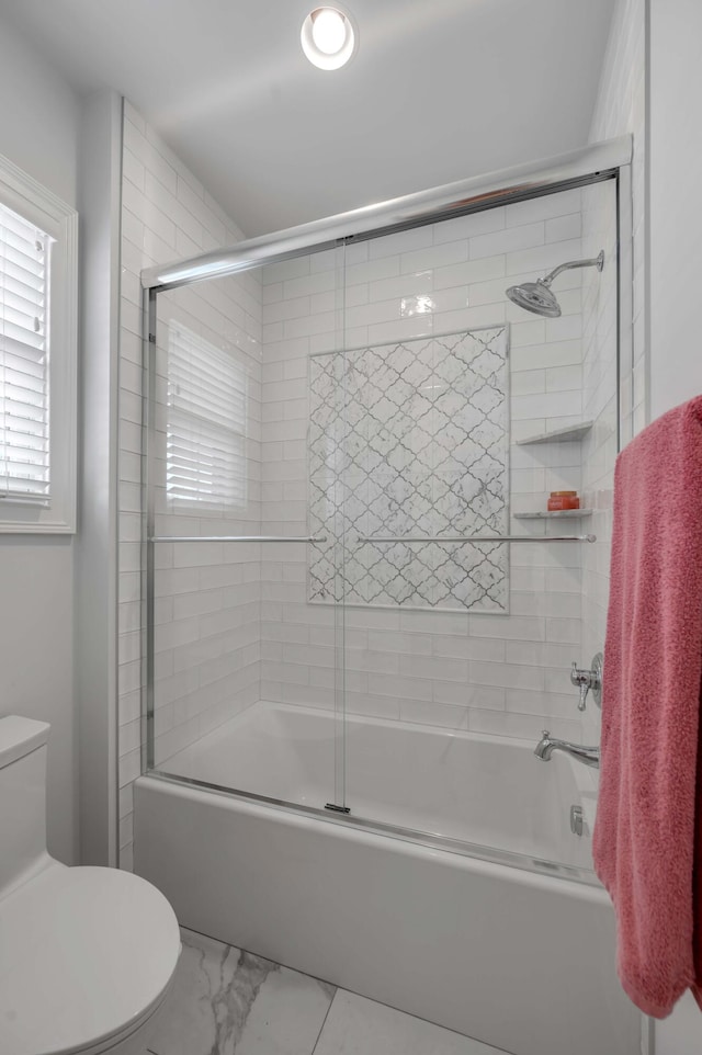 full bathroom featuring shower / bath combination with glass door, marble finish floor, and toilet