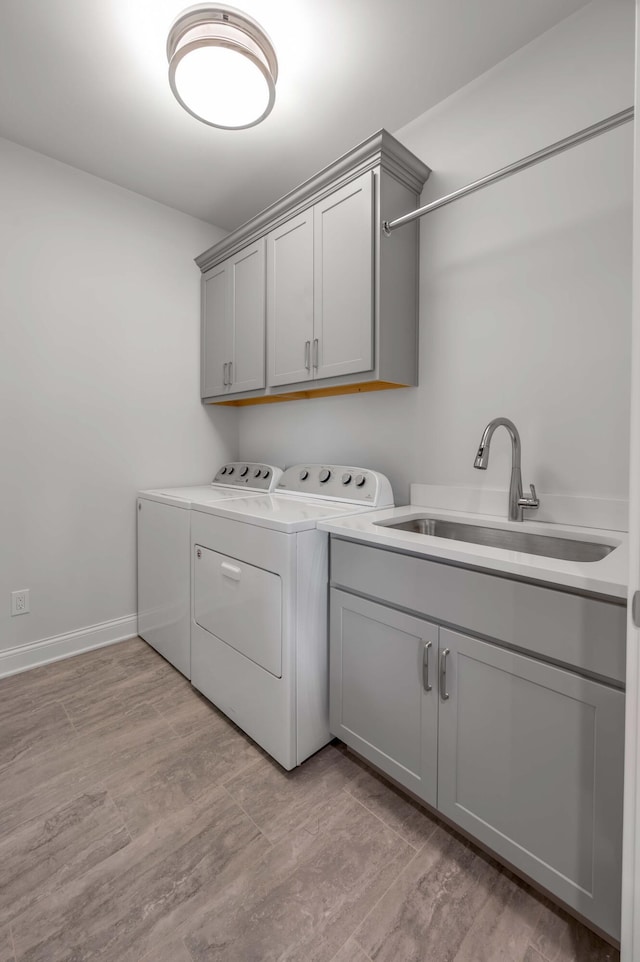 washroom featuring washer and clothes dryer, cabinet space, light wood-style floors, and a sink