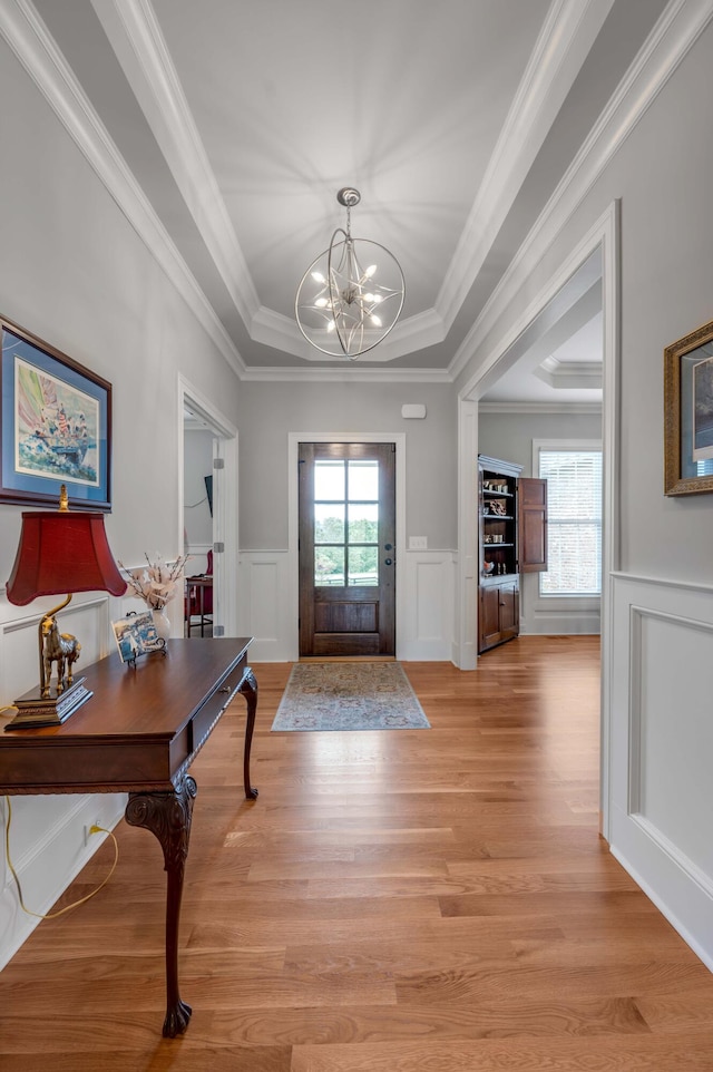 foyer with an inviting chandelier, light wood-style floors, and wainscoting