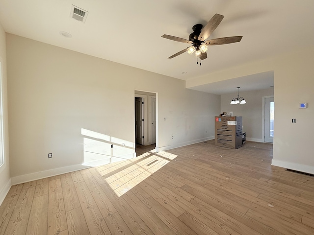 unfurnished living room featuring ceiling fan with notable chandelier and light hardwood / wood-style flooring