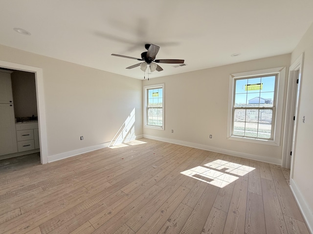 interior space featuring ceiling fan, light wood-type flooring, and multiple windows