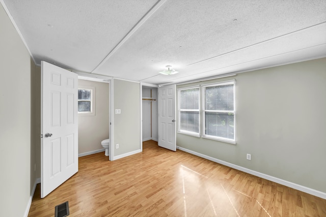 unfurnished room featuring light hardwood / wood-style flooring and a textured ceiling