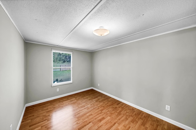 unfurnished room with a textured ceiling, ornamental molding, and hardwood / wood-style floors