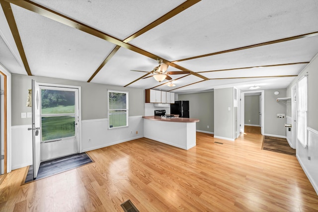 unfurnished living room with ceiling fan, a textured ceiling, and light wood-type flooring