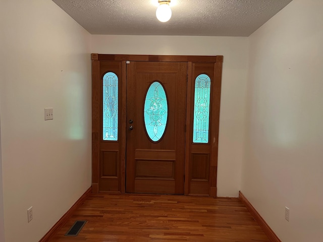 foyer with wood-type flooring and a textured ceiling