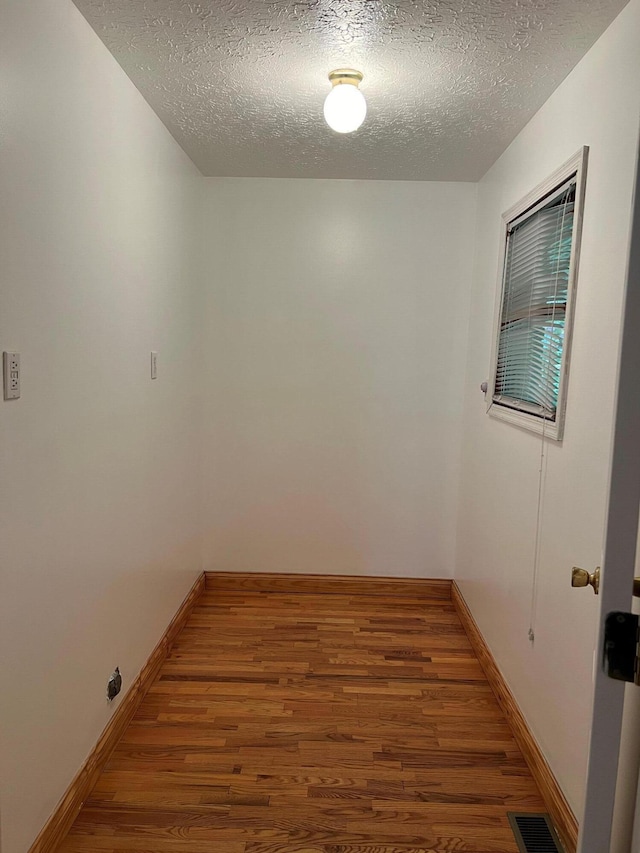 unfurnished room with wood-type flooring and a textured ceiling