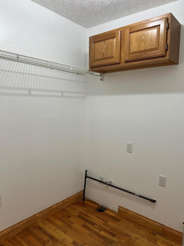 laundry area with a textured ceiling, dark hardwood / wood-style floors, and cabinets