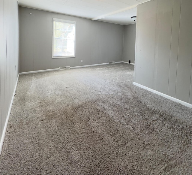 carpeted empty room with beam ceiling