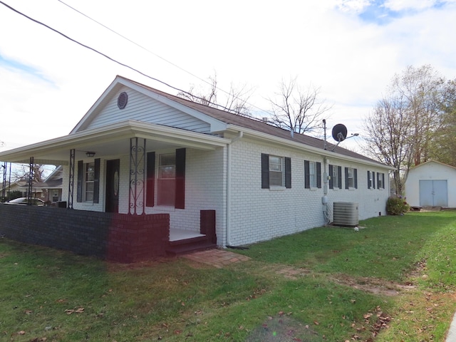 view of front facade featuring cooling unit, covered porch, a front yard, and a storage unit