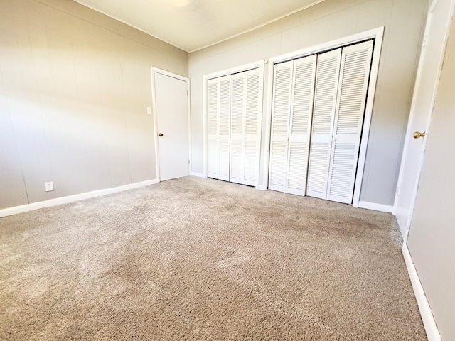 unfurnished bedroom with carpet flooring and two closets