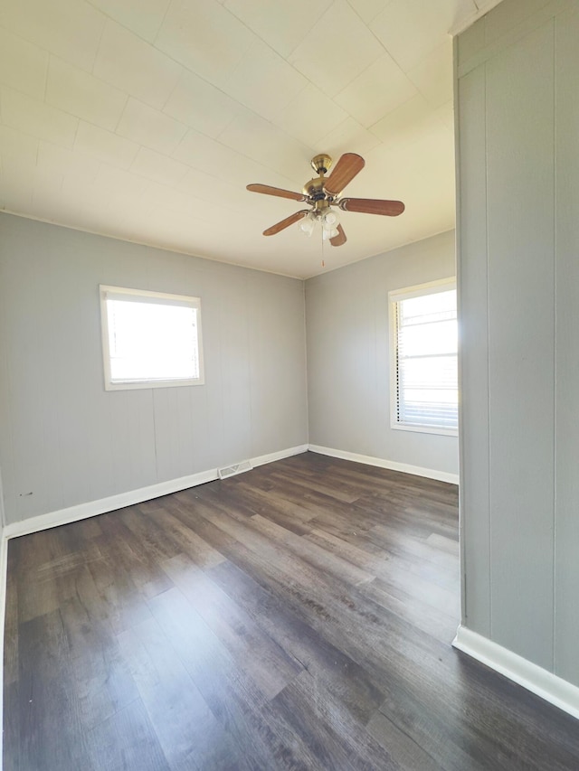 empty room featuring ceiling fan, dark hardwood / wood-style flooring, and a healthy amount of sunlight