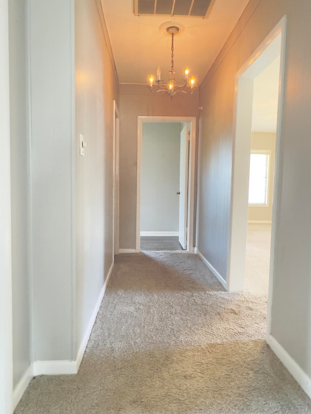 corridor with carpet, a notable chandelier, and ornamental molding