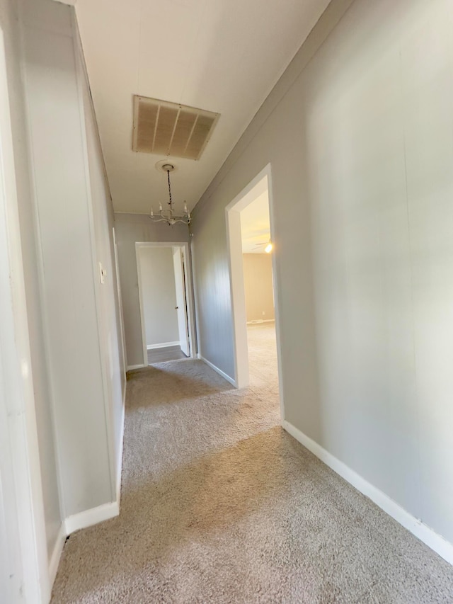 corridor featuring a chandelier and light colored carpet