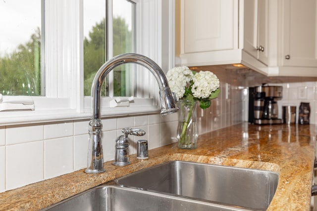 details featuring white cabinetry, backsplash, light stone counters, and sink