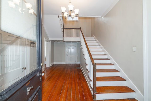 foyer featuring dark hardwood / wood-style flooring, ornamental molding, and a chandelier