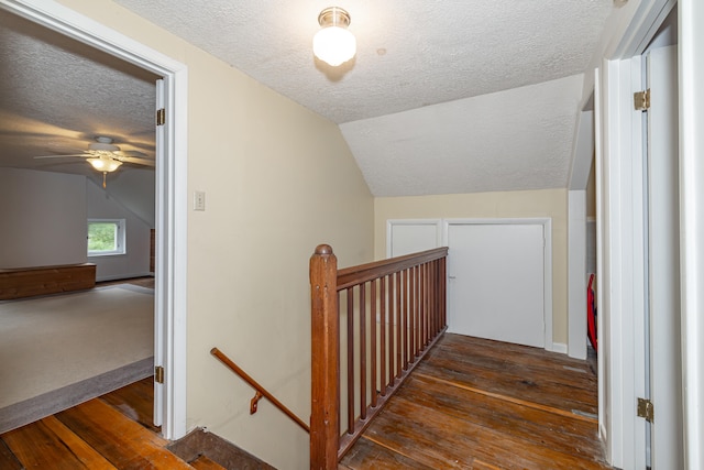 staircase with ceiling fan, vaulted ceiling, a textured ceiling, and hardwood / wood-style floors