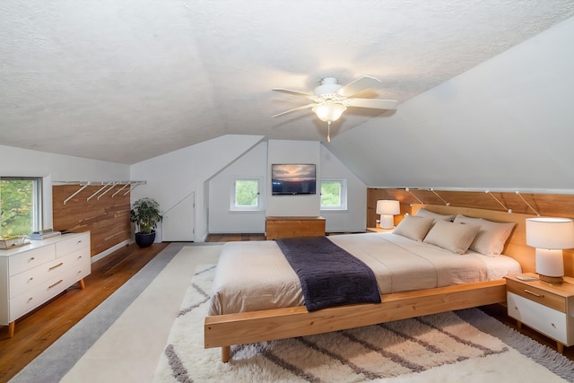 bedroom with ceiling fan, wood-type flooring, a textured ceiling, and vaulted ceiling