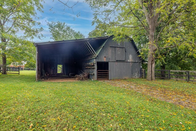 view of barn featuring a yard, a carport, and fence