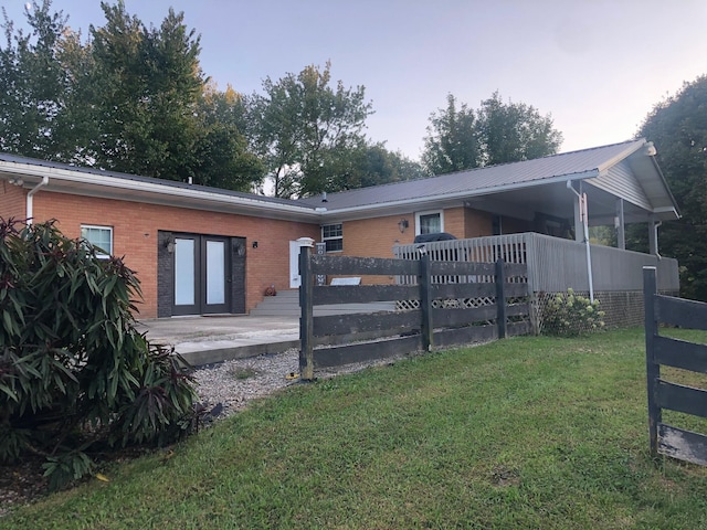 back of property with metal roof, brick siding, fence, a yard, and french doors