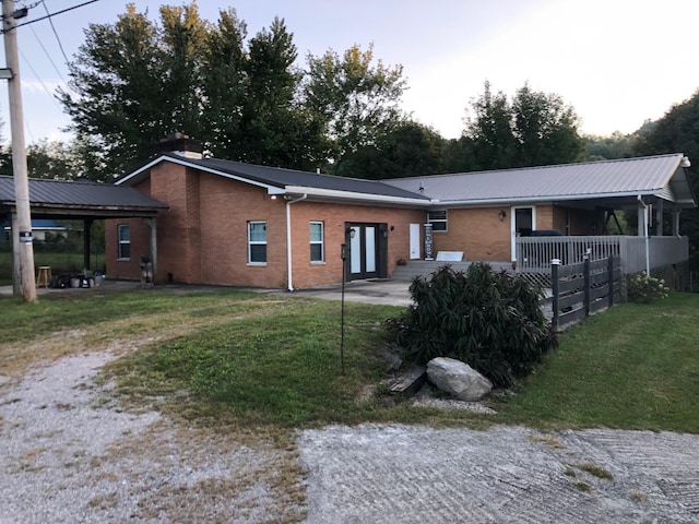 back of property featuring a yard, metal roof, brick siding, and a patio area