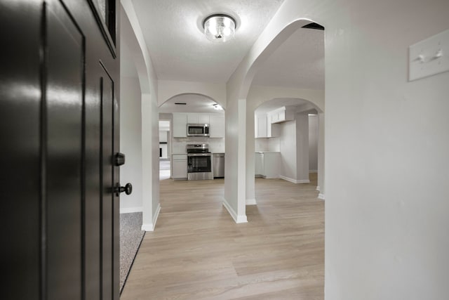 hall featuring a textured ceiling and light wood-type flooring