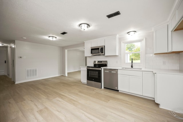 kitchen with light hardwood / wood-style flooring, white cabinets, stainless steel appliances, and sink