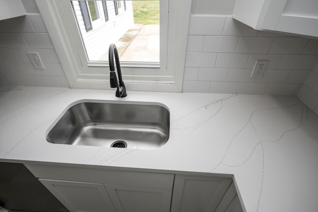 interior details with sink, light stone counters, and tasteful backsplash