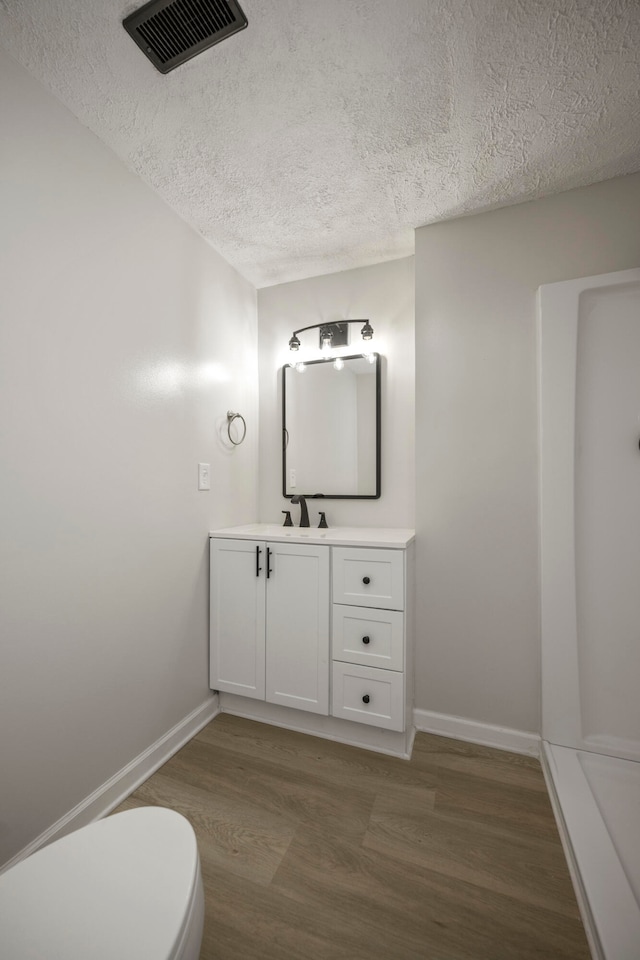 bathroom featuring vanity, toilet, a textured ceiling, and hardwood / wood-style floors