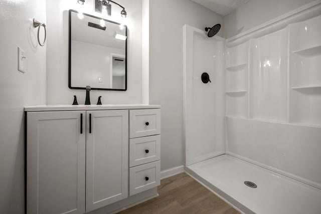 bathroom featuring vanity, walk in shower, a textured ceiling, and hardwood / wood-style floors