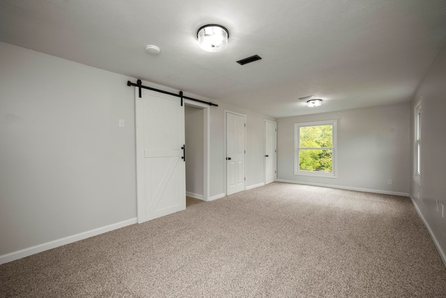 empty room featuring a barn door and carpet