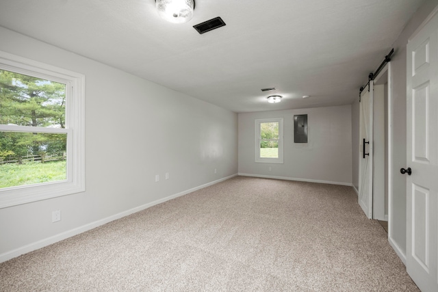 empty room featuring carpet, a barn door, and electric panel