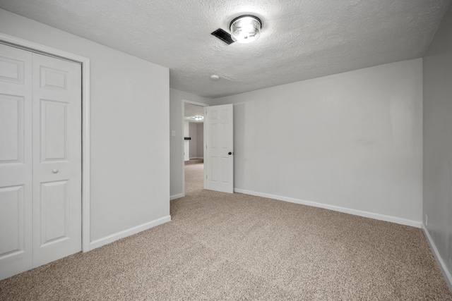 unfurnished bedroom featuring a closet, a textured ceiling, and carpet