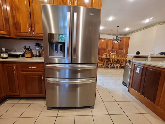 kitchen with pendant lighting, light tile patterned flooring, stainless steel fridge with ice dispenser, backsplash, and ornamental molding