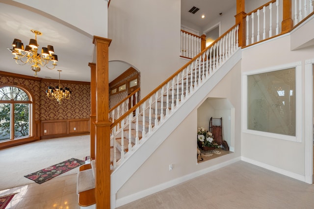 stairway featuring a chandelier, carpet flooring, and crown molding