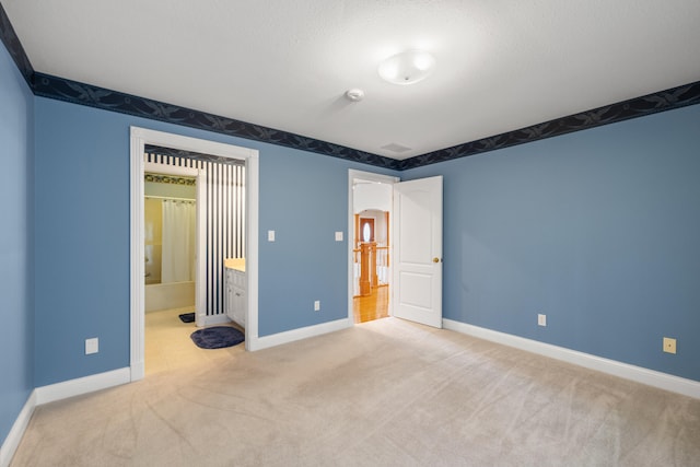 unfurnished bedroom featuring light carpet, a textured ceiling, and ensuite bathroom