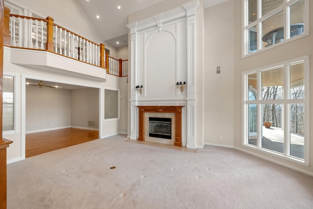 unfurnished living room with ceiling fan, a fireplace, light carpet, and high vaulted ceiling