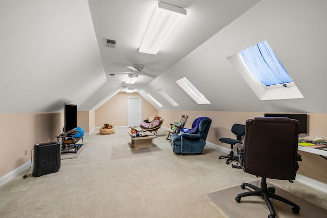 carpeted office featuring vaulted ceiling with skylight, a textured ceiling, and ceiling fan