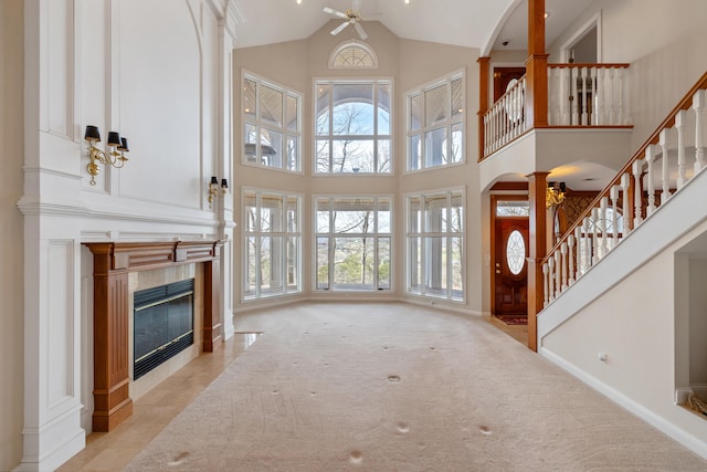 living room with ceiling fan, a fireplace, light carpet, and high vaulted ceiling