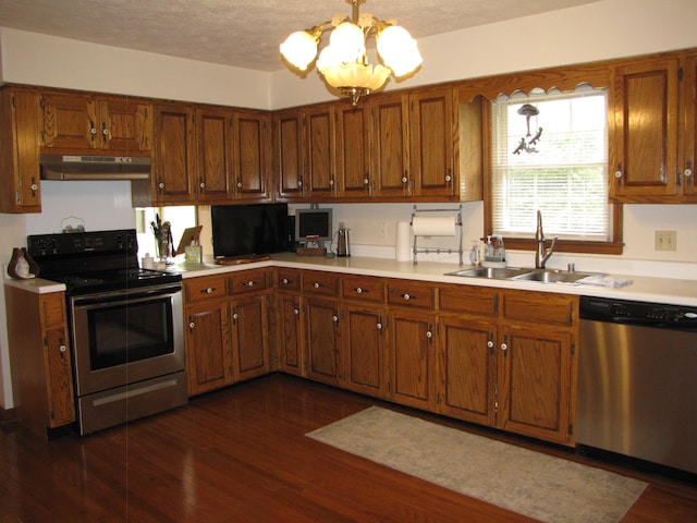 kitchen featuring hanging light fixtures, sink, a chandelier, appliances with stainless steel finishes, and dark hardwood / wood-style flooring