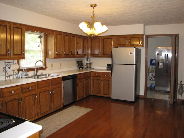 kitchen featuring dark hardwood / wood-style floors, sink, an inviting chandelier, stainless steel appliances, and decorative light fixtures