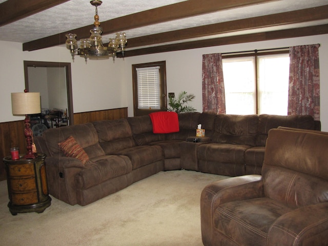 carpeted living room featuring a notable chandelier, wooden walls, a textured ceiling, and beamed ceiling