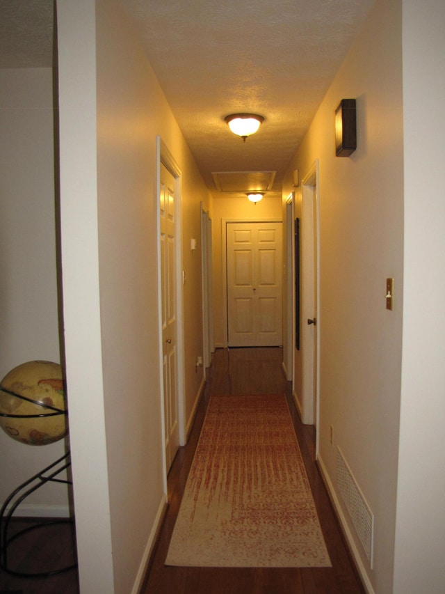 hallway featuring a textured ceiling and dark hardwood / wood-style flooring