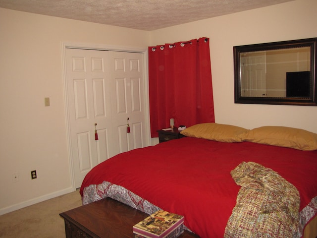 bedroom with a textured ceiling, carpet, and a closet