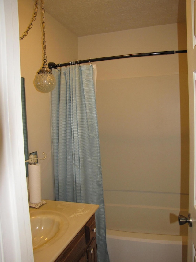 bathroom with shower / tub combo with curtain, a textured ceiling, and vanity