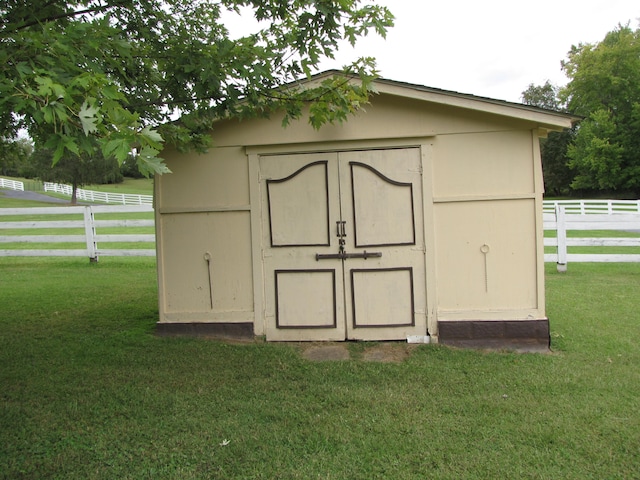 view of outbuilding featuring a rural view and a lawn