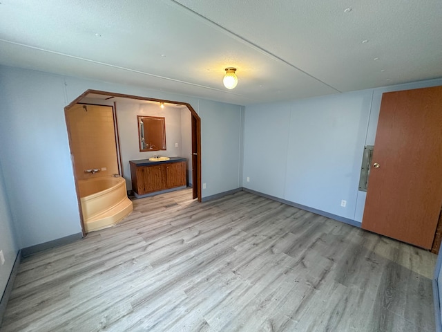 unfurnished bedroom featuring connected bathroom and light hardwood / wood-style floors