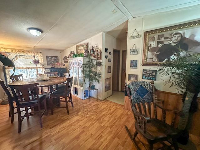 dining room with wood-type flooring, lofted ceiling, and a textured ceiling