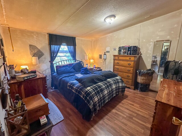 bedroom featuring a textured ceiling and dark hardwood / wood-style floors