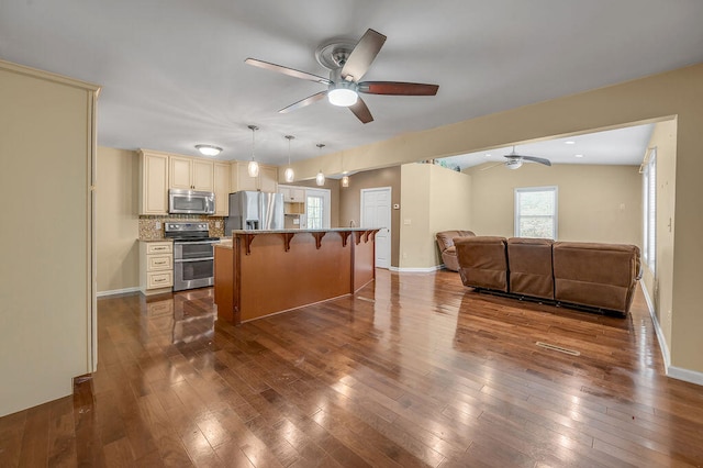 kitchen featuring a kitchen bar, hanging light fixtures, a kitchen island, appliances with stainless steel finishes, and ceiling fan