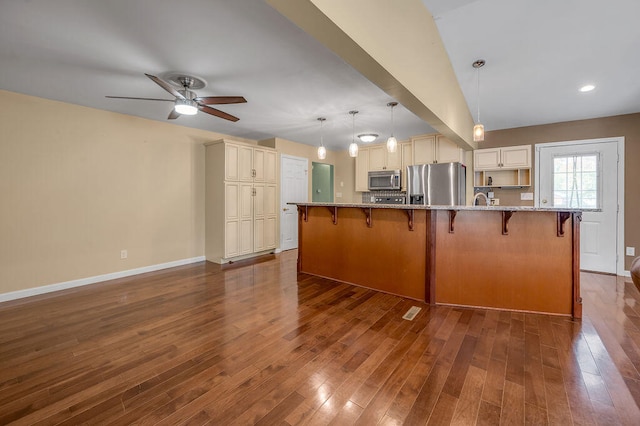 kitchen featuring ceiling fan, hanging light fixtures, appliances with stainless steel finishes, vaulted ceiling, and dark hardwood / wood-style flooring